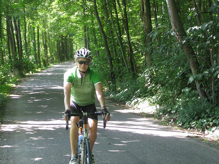 Woman on a bike on a road going through the forest